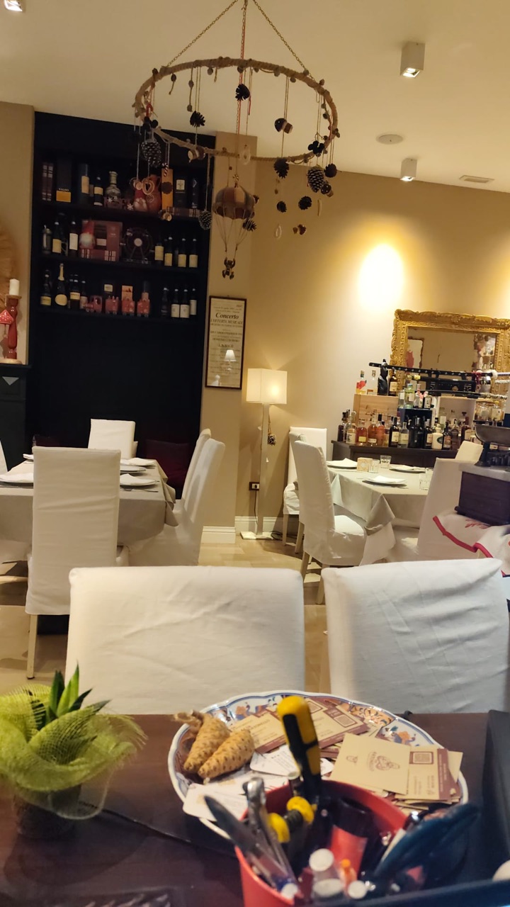 Sala interna della Pizzeria Da Antonello a Foggia con tavoli apparecchiati e scaffale di vini